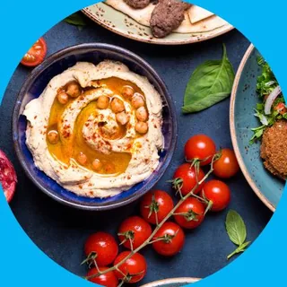 A plate of hummus with chickpeas and cherry tomatoes